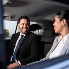 Coworkers talking inside a taxi during an airport transfer